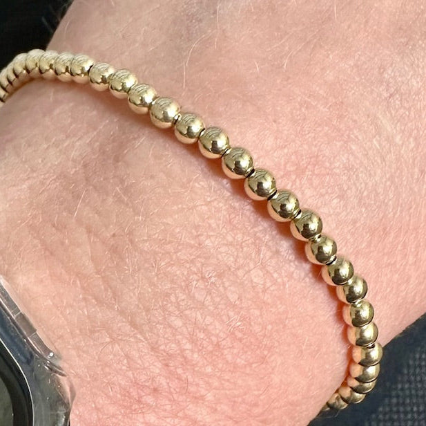 Close up of a 14K gold filled 4mm bead bracelet worn on a wrist