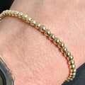 Close up of a 14K gold filled 4mm bead bracelet worn on a wrist