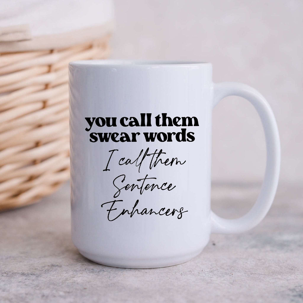 White ceramic coffee mug with text that reads You call them swear words I call them Sentence Enhancers.