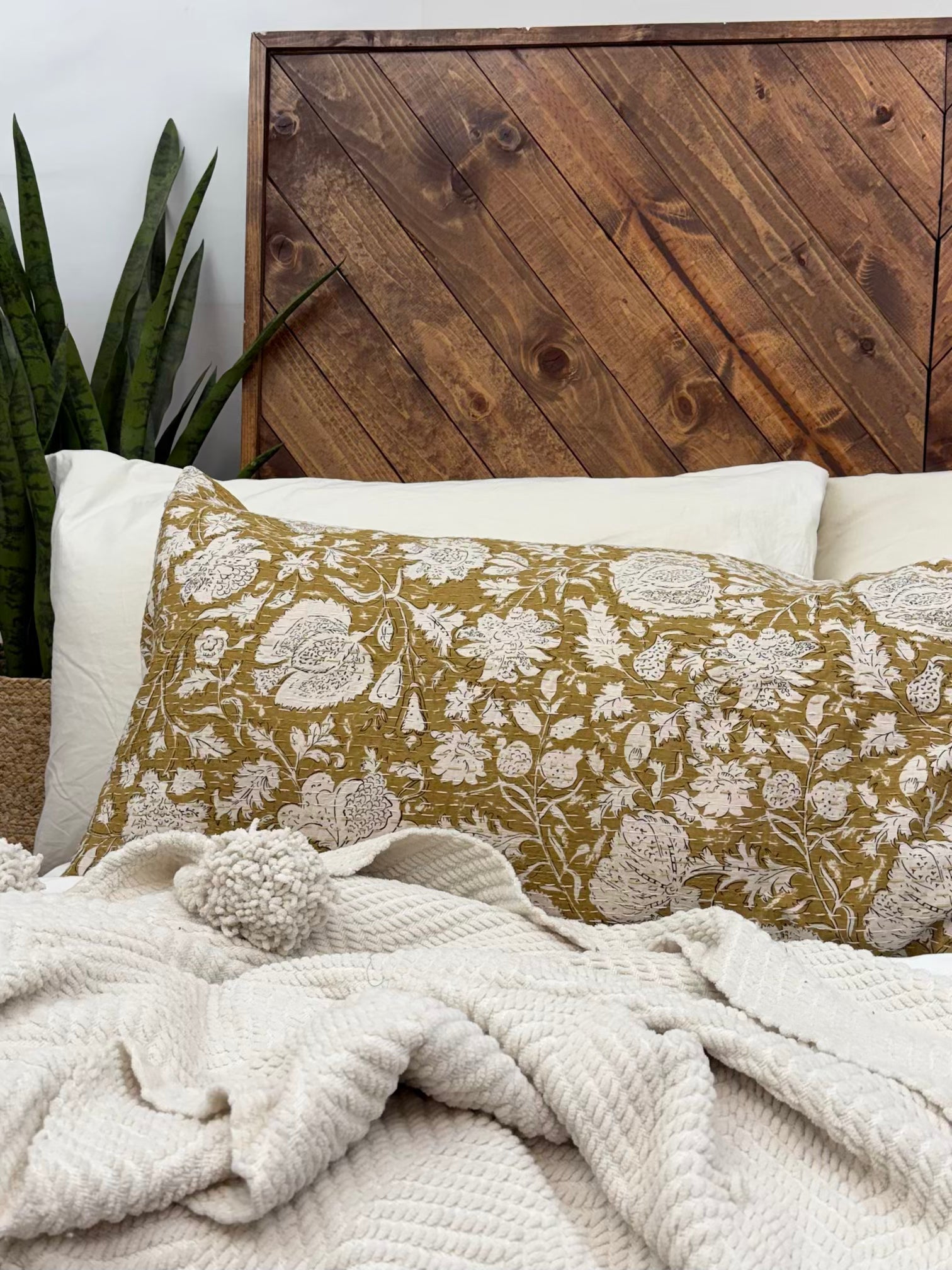 Close up of yellow floral block print cotton Kantha sham on a bed with white textured throw blanket