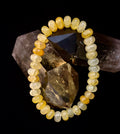 Yellow Agate Rondelle bead bracelet resting on dark crystal formations