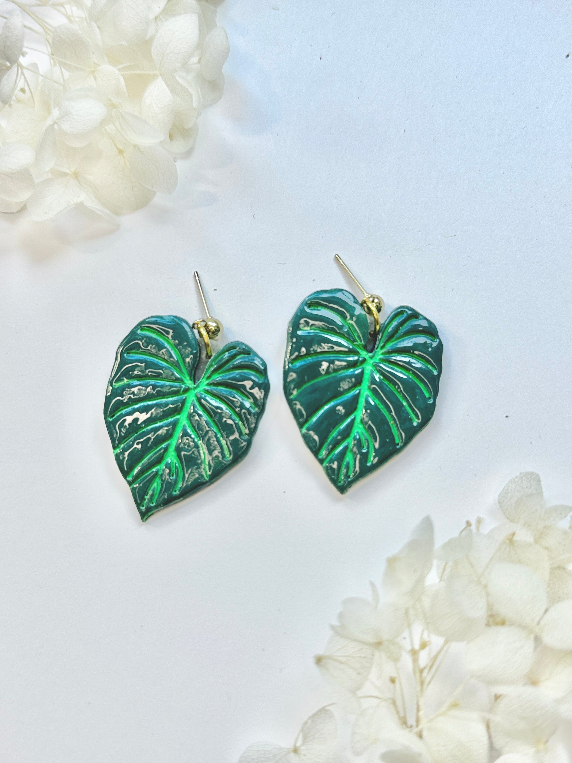 Philodendron Gloriosum botanical earrings featuring emerald green leaves and gold accents.