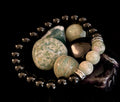 A close up view of a White-Grayish Green Natural Stone Stretchy Unisex Bracelet with dark beads and silver spacers.