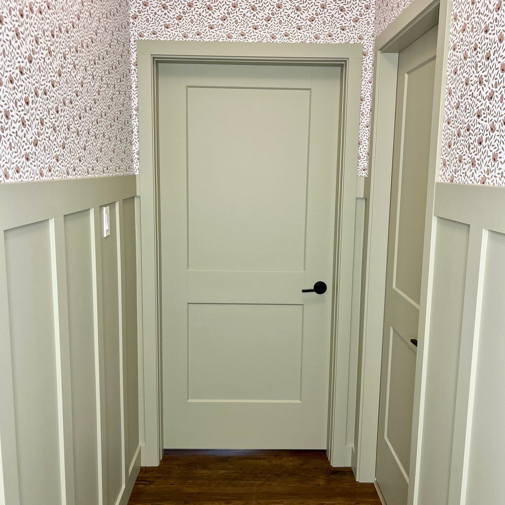 Close up of Eliana floral pattern wallpaper in sage green and off-white on a living room wall