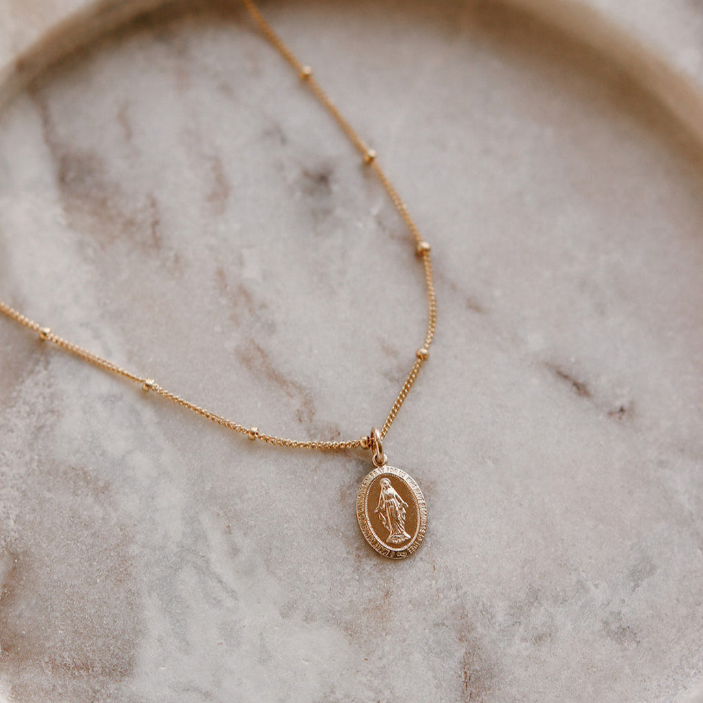 Gold necklace with a pendant on a marble surface