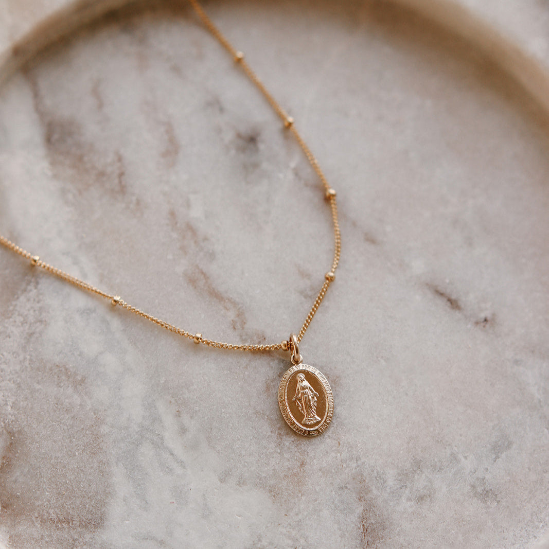 Gold necklace with a pendant on a marble surface