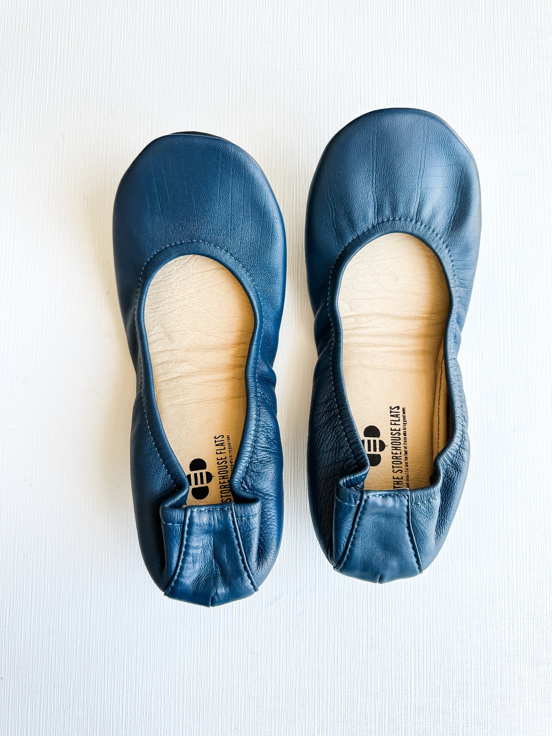 A pair of navy blue Signature ballet flats from The Storehouse Flats viewed from above and showing the treaded sole.