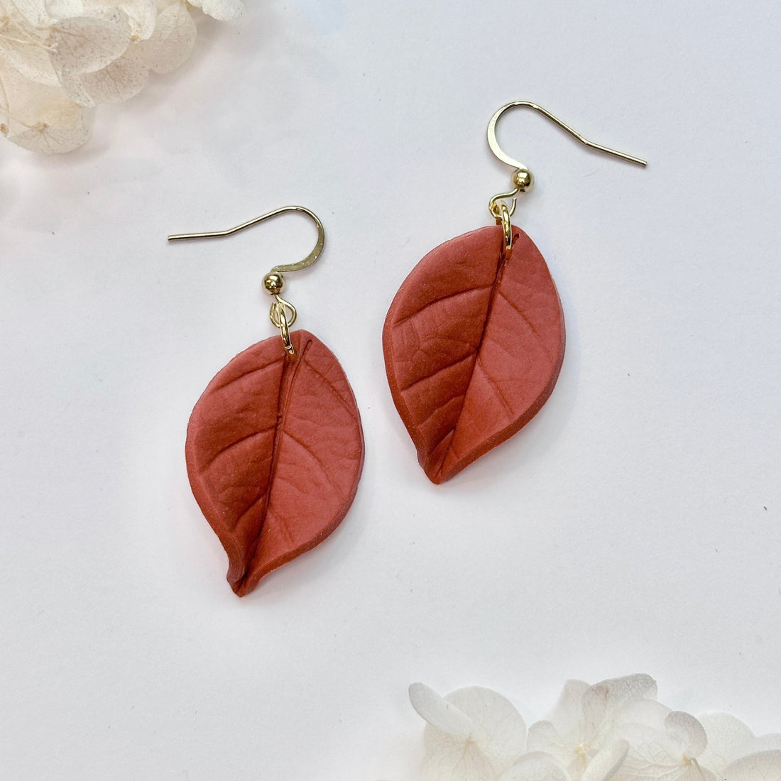 Bohemian-style Hoya Coriacea leaf earrings in terracotta and muted-green shades with gold accents.