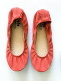 A pair of coral nubuck suede ballet flats featuring a flexible construction and a rubberized hexagon-patterned sole.