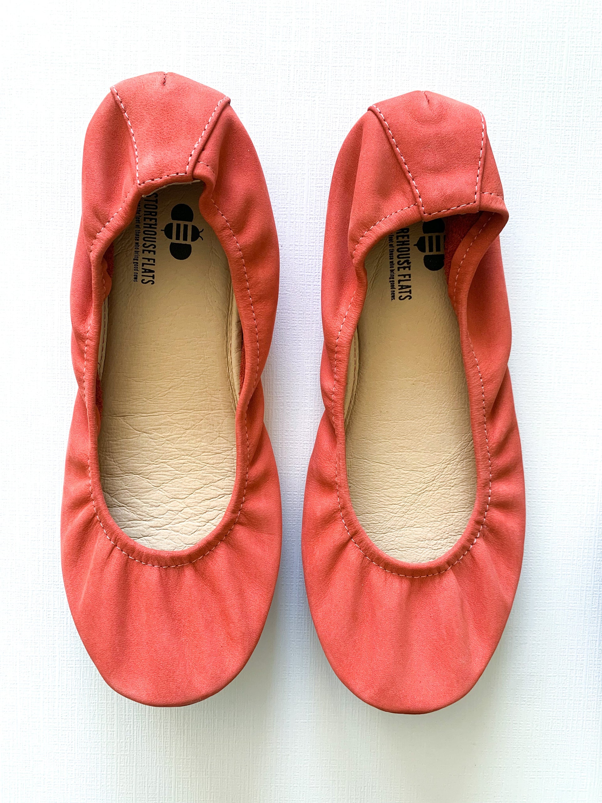 A pair of coral nubuck suede ballet flats featuring a flexible construction and a rubberized hexagon-patterned sole.