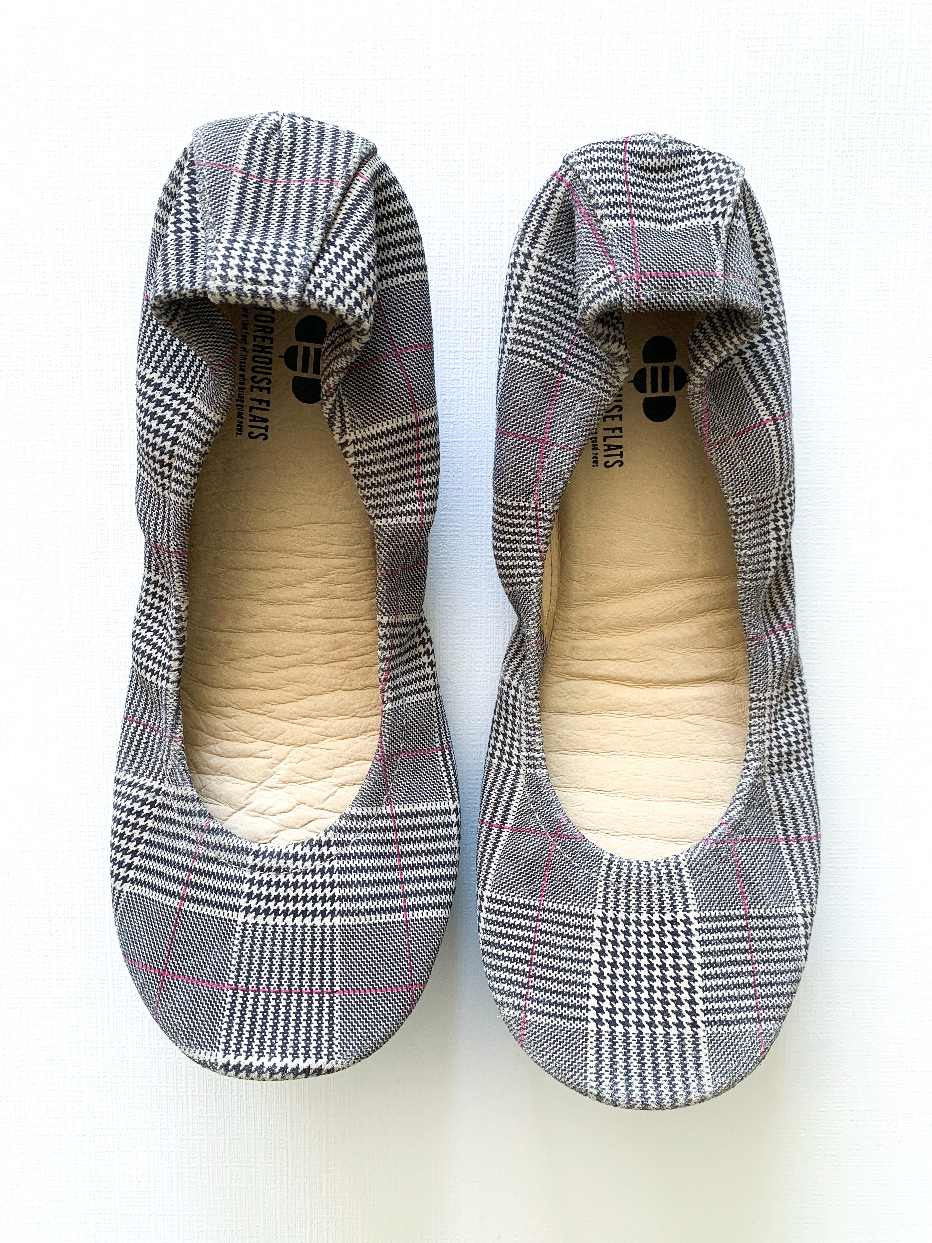 A pair of women's ballet flats with a classic plaid pattern and pink detail accents, shown from top-down and bottom-up views.