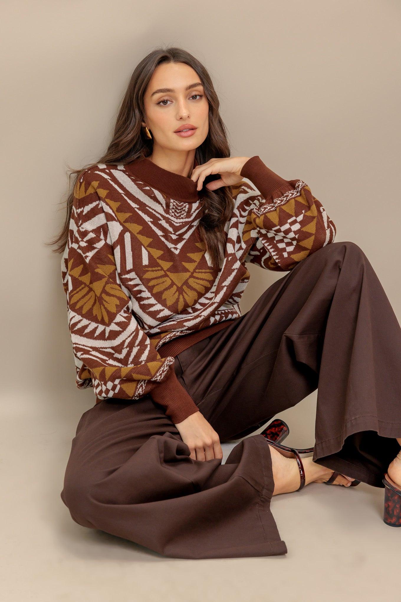 Model wearing a brown and tan geometric patterned mock neck pullover sweater with blouson sleeves.
