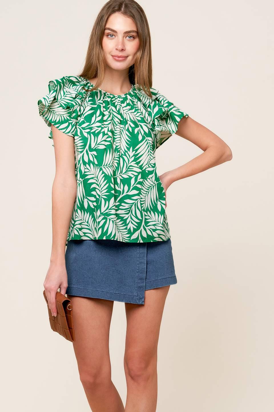 Woman wearing a green and white tropical leaf print woven top with layered ruffle sleeves