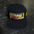 A black snapback cap with yellow and red embroidered text reading INVINCIBLE on the front.