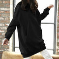 A woman wearing a long-sleeve black solid sweatshirt with a relaxed, loose-fit design.