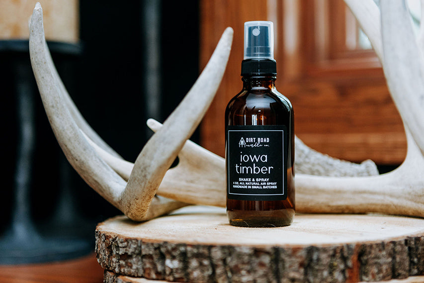 Iowa Timber room spray in amber bottle next to deer antlers on wood slice