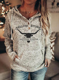 Woman wearing a grey hooded pullover with a Yellowstone Dutton Ranch graphic print and front kangaroo pocket