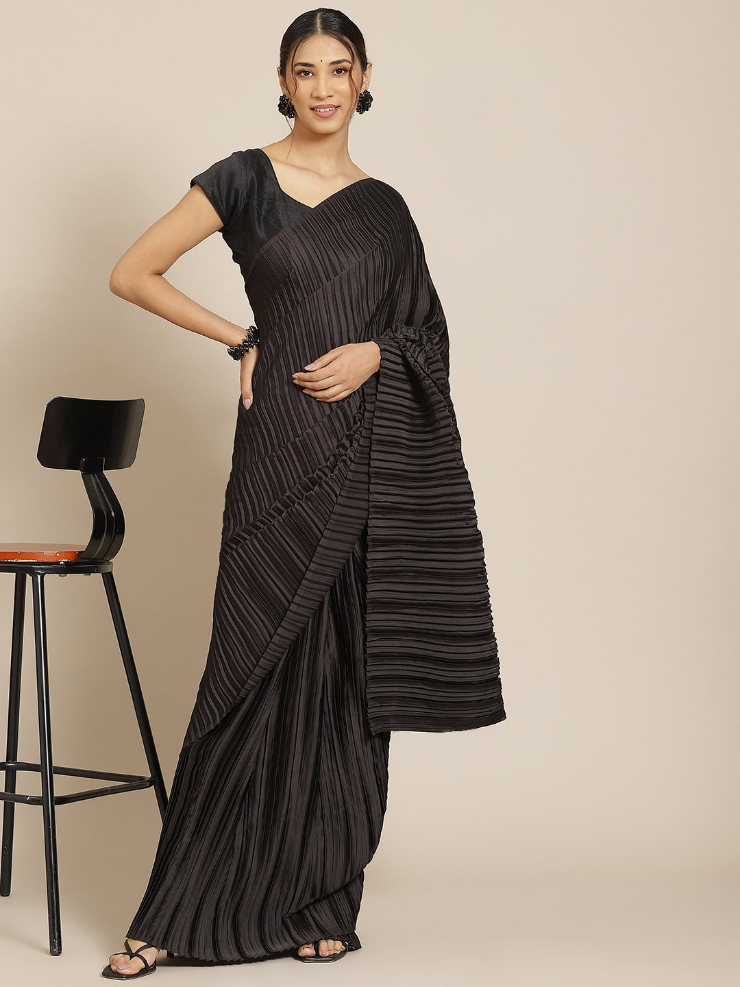 Black satin designer saree with pleated detailing and matching blouse.