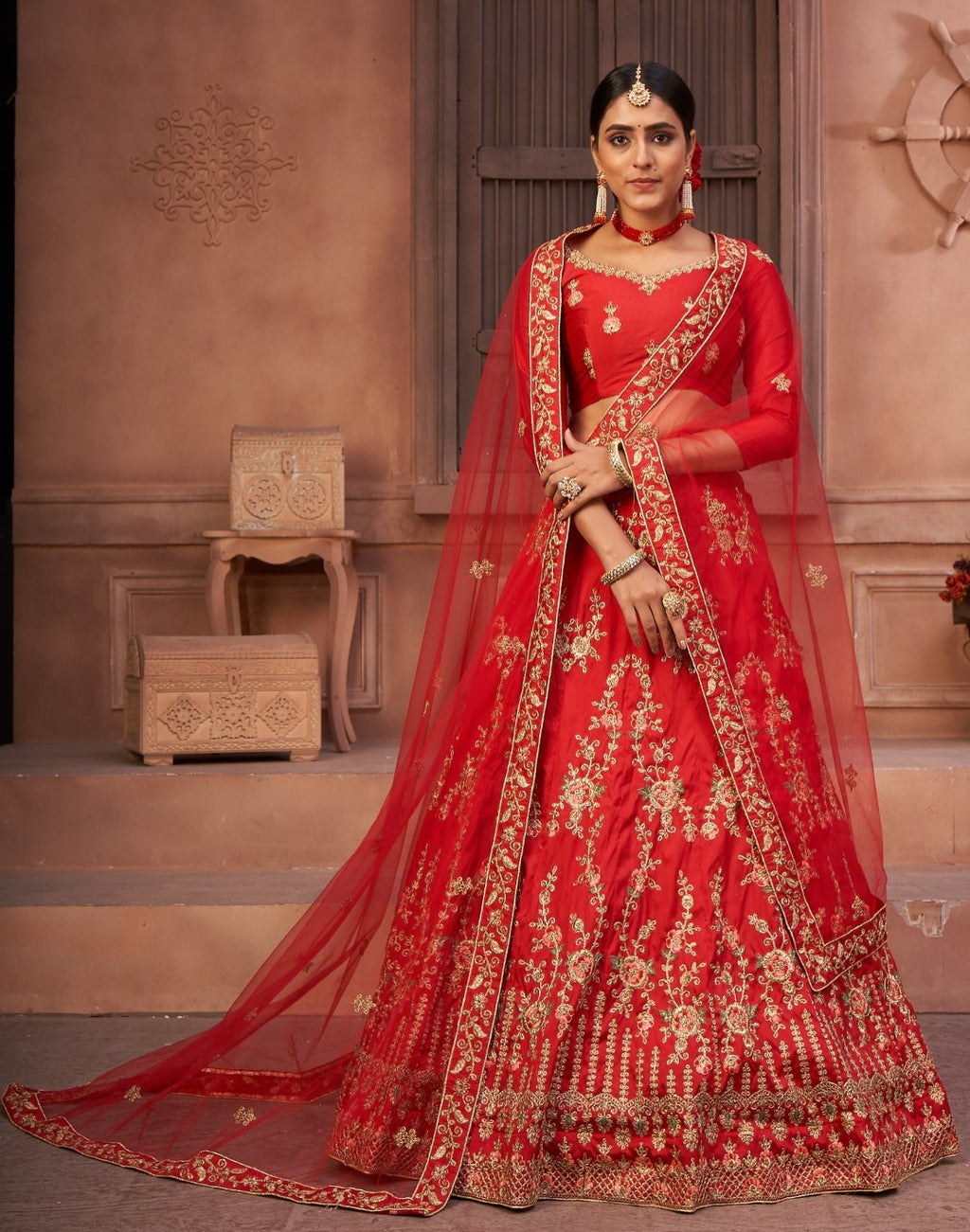 Women wearing a red taffeta silk lehenga choli with detailed thread embroidery.
