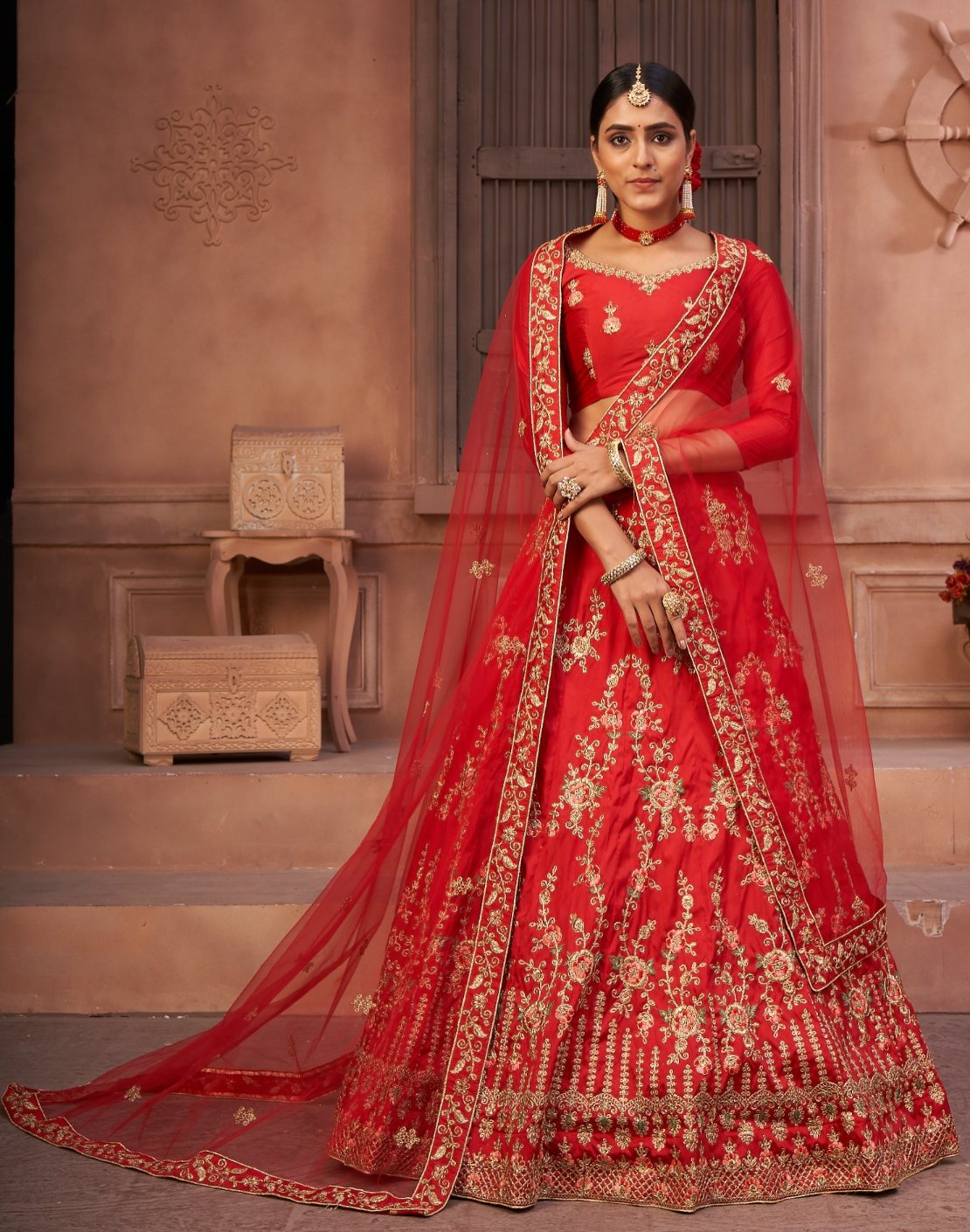 Women wearing a red taffeta silk lehenga choli with detailed thread embroidery.