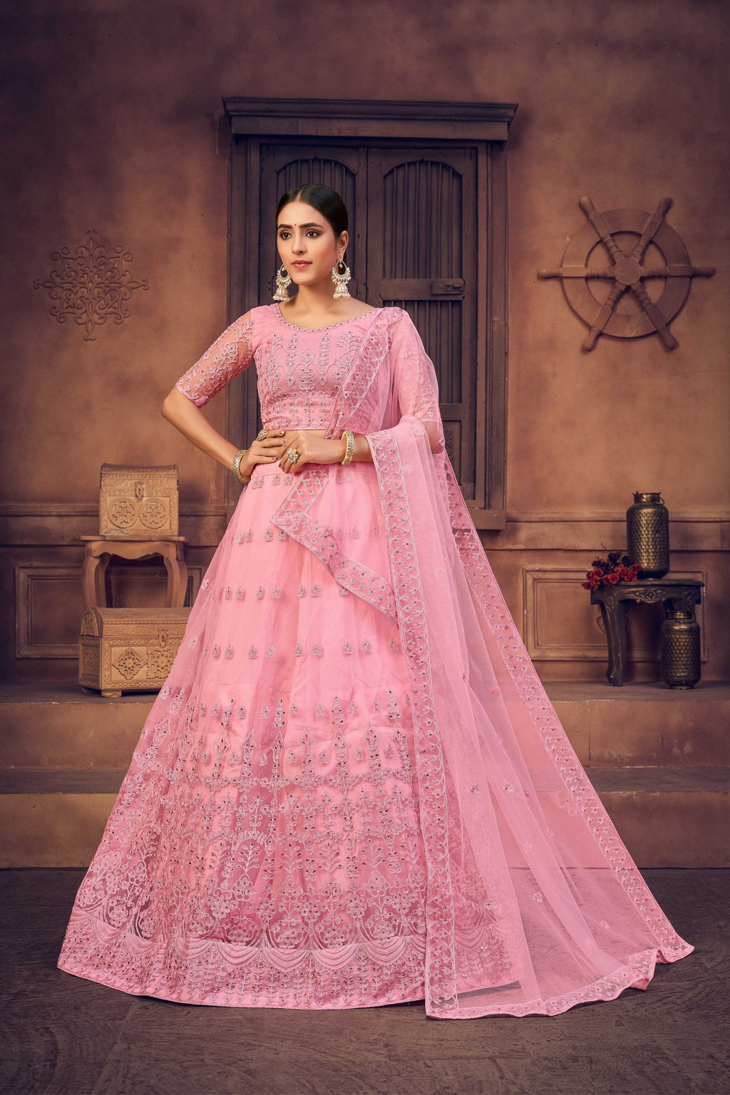 Little girl wearing a beautiful baby pink net lehenga choli with intricate thread embroidery.