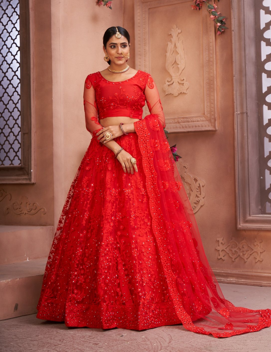 Vibrant red net lehenga choli set with detailed thread embroidery for festive occasions