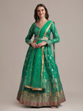 Woman wearing a Rama colored Jacquard Silk Lehenga Choli with gold woven work.