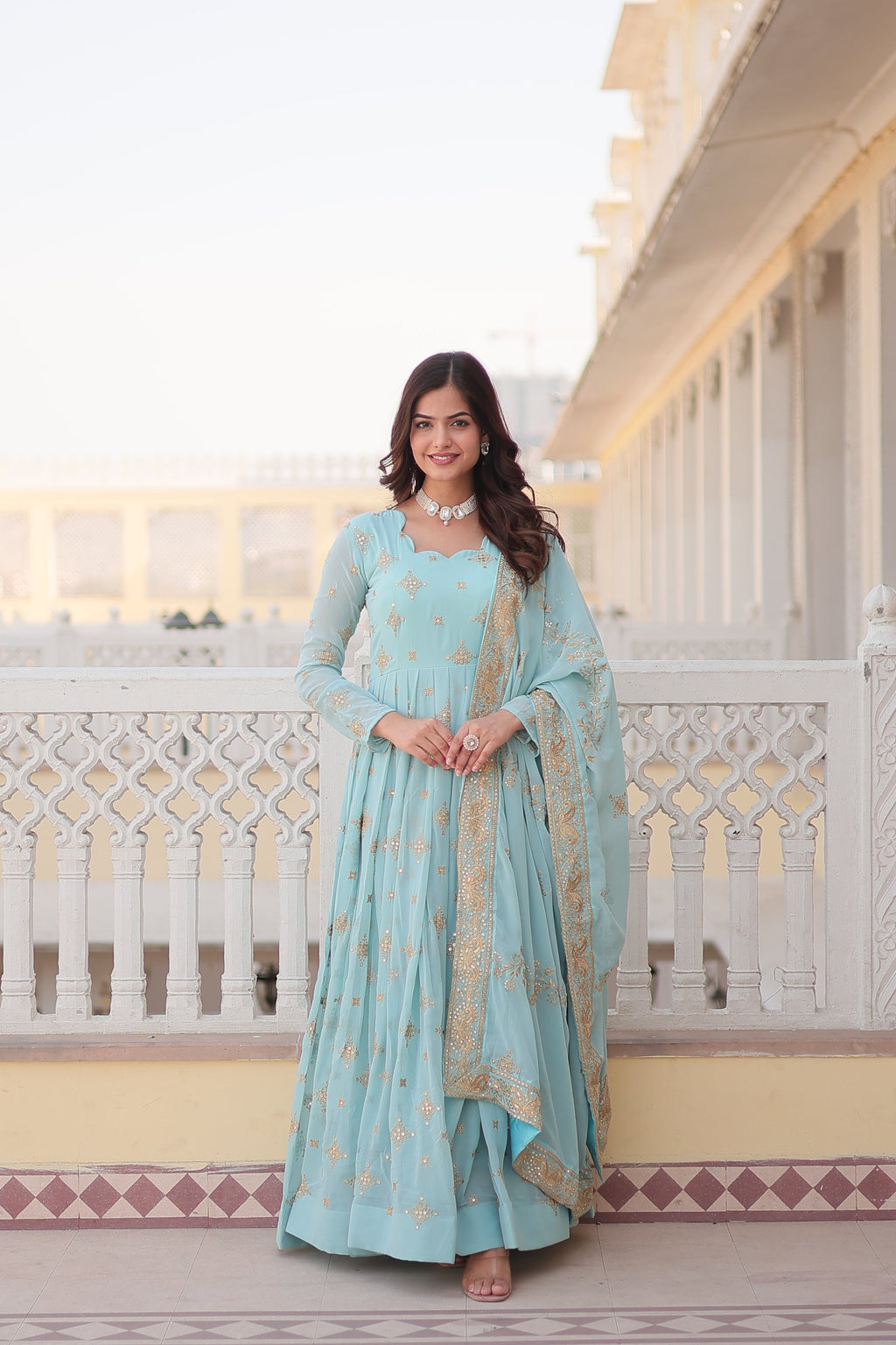 Woman wearing a sky blue faux georgette Anarkali kurta with intricate sequins and zari embroidery.