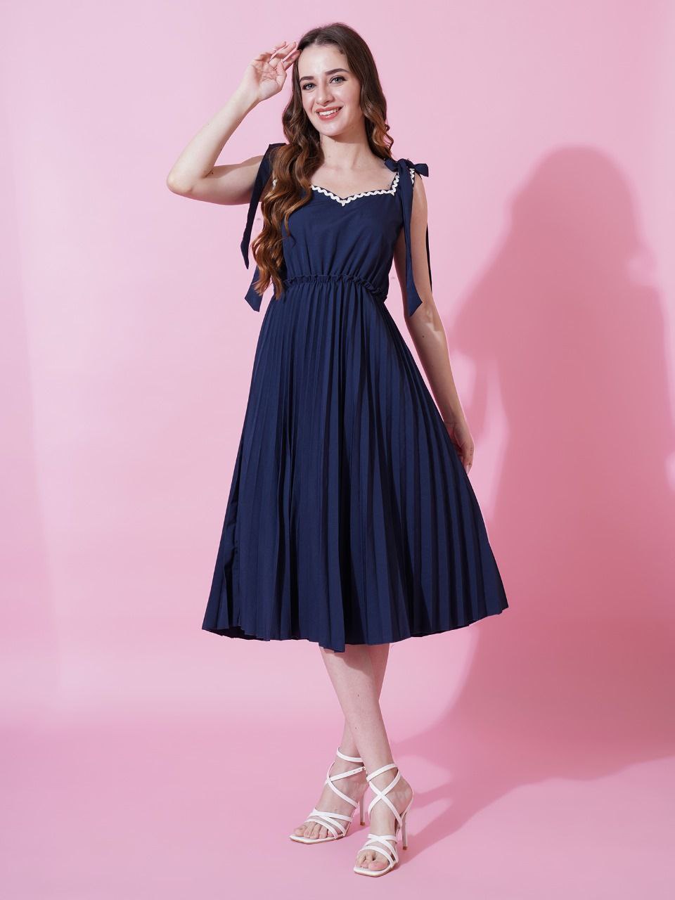 Woman wearing a Navy Blue sleeveless crushed crepe flared dress with shoulder tie-ups.