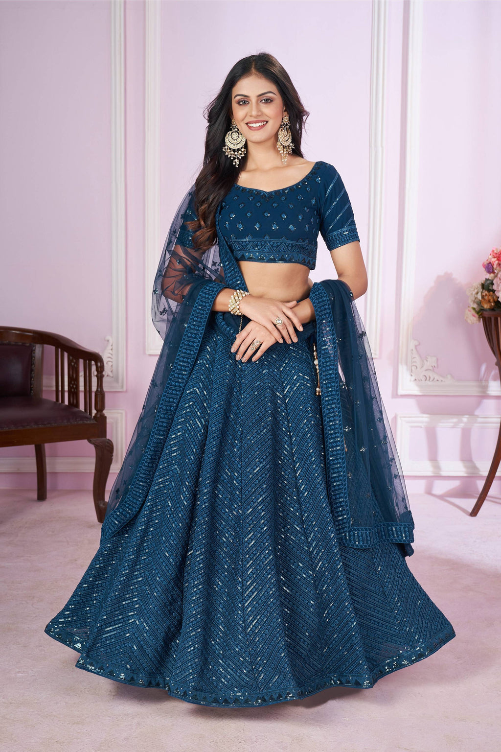 Woman wearing a Teal Georgette lehenga choli with intricate sequins and thread embroidery
