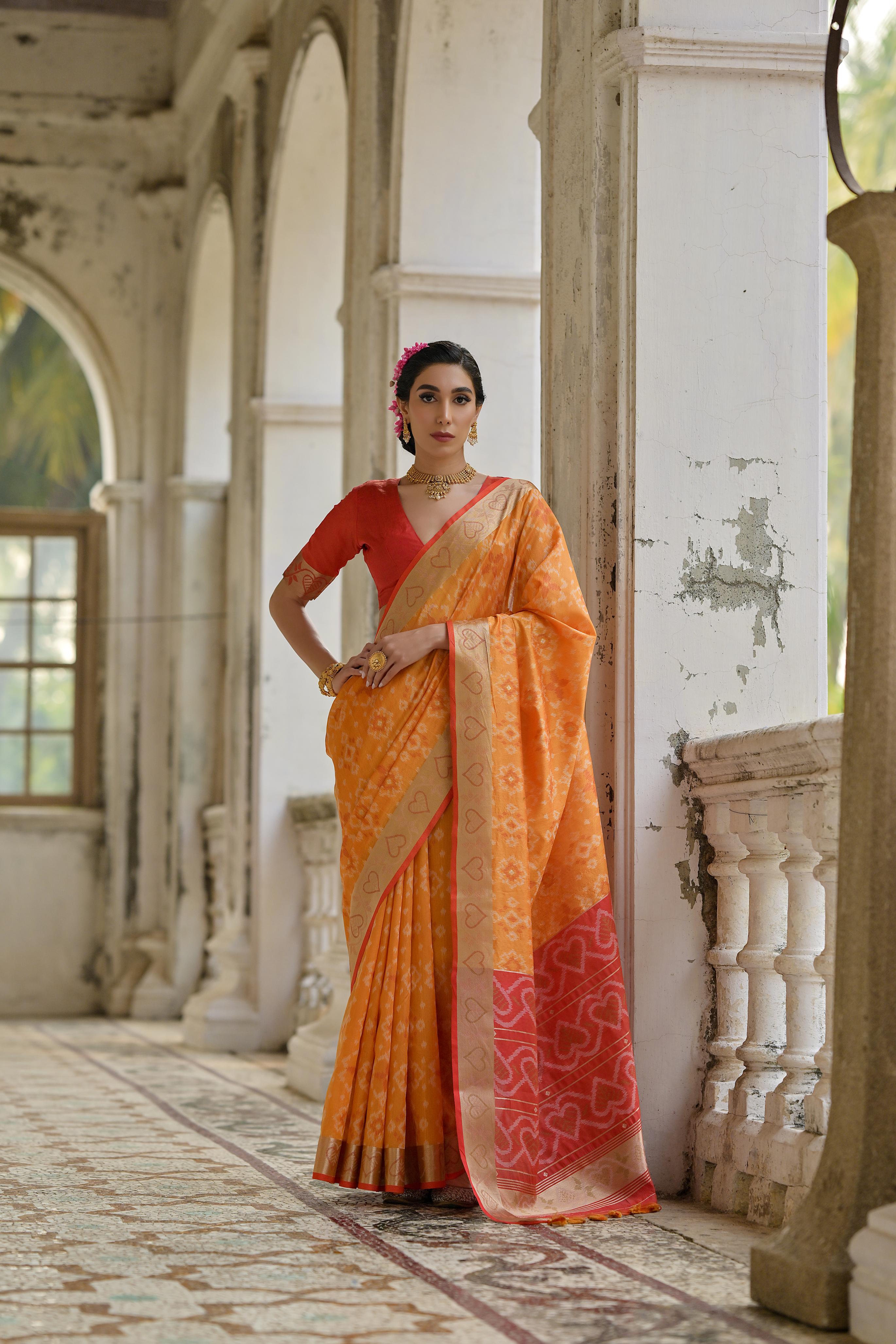Close up of orange soft raw silk saree with intricate gold zari woven border