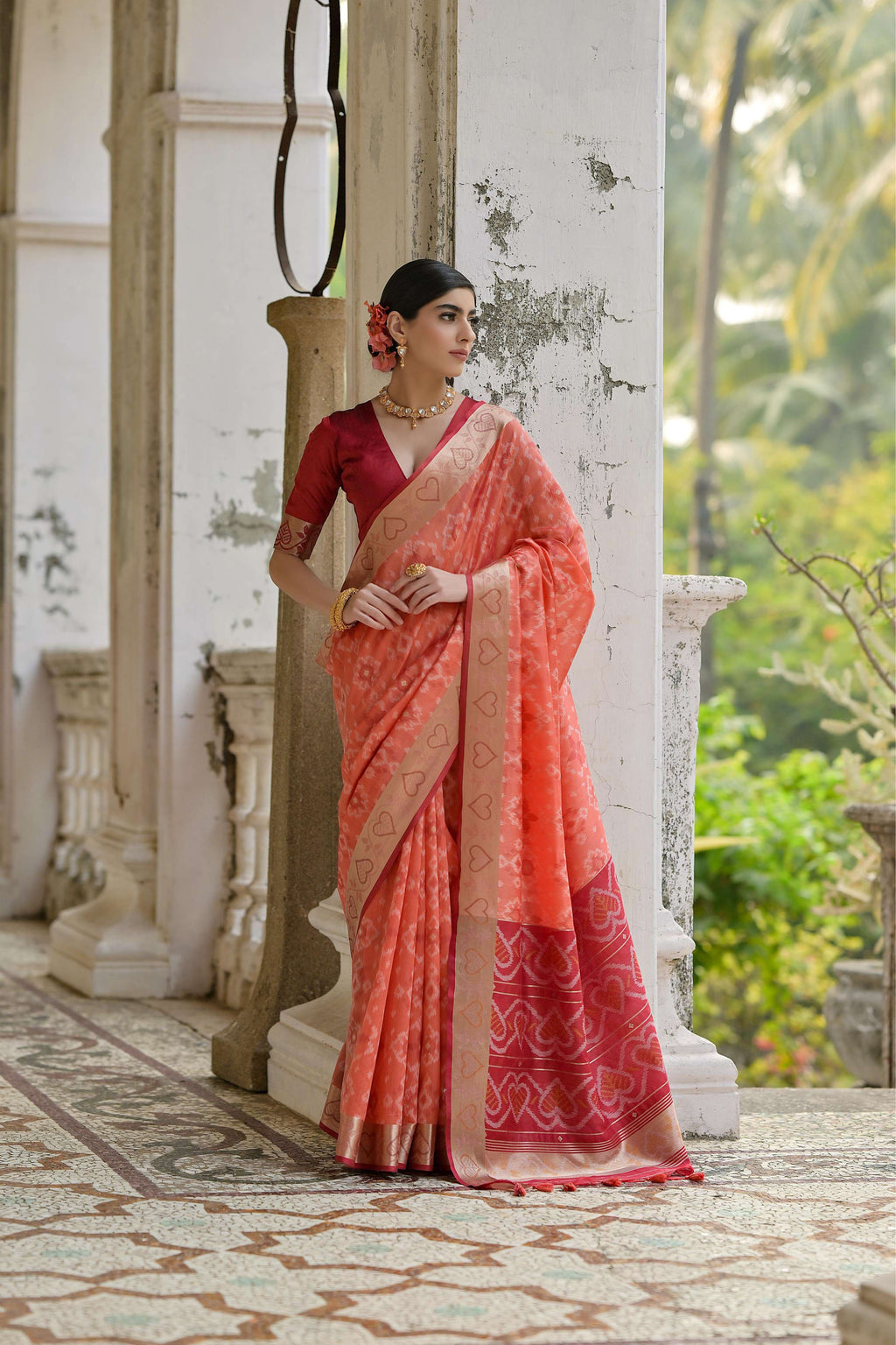 Elegant coral soft raw silk saree with intricate gold zari woven details and matching blouse
