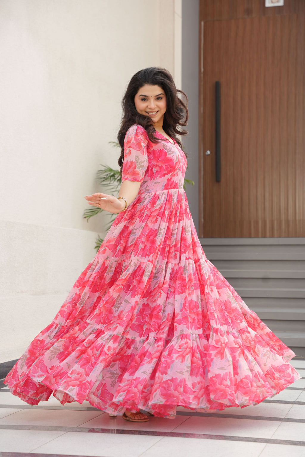 Woman wearing a Pink Faux Georgette long Anarkali dress with floral prints and full sleeves