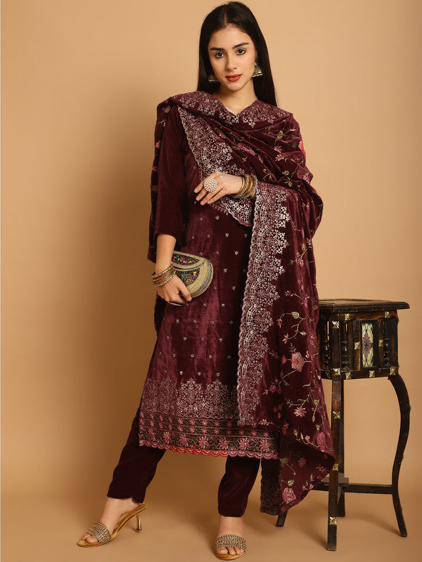 Woman wearing a maroon velvet straight kurta with floral Resham, Jari, and sequin work paired with matching trousers.
