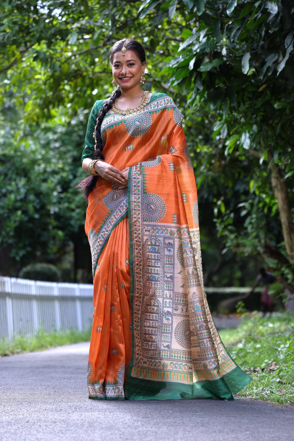 Orange Soft Tussar silk saree with traditional Madhubani and Warli folk art prints.
