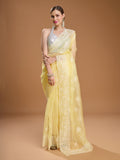 Woman wearing a yellow net designer saree with elegant sequins embroidery and a matching blouse.