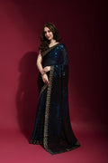 Woman wearing a blue georgette saree with intricate sequence embroidery and matching blouse.