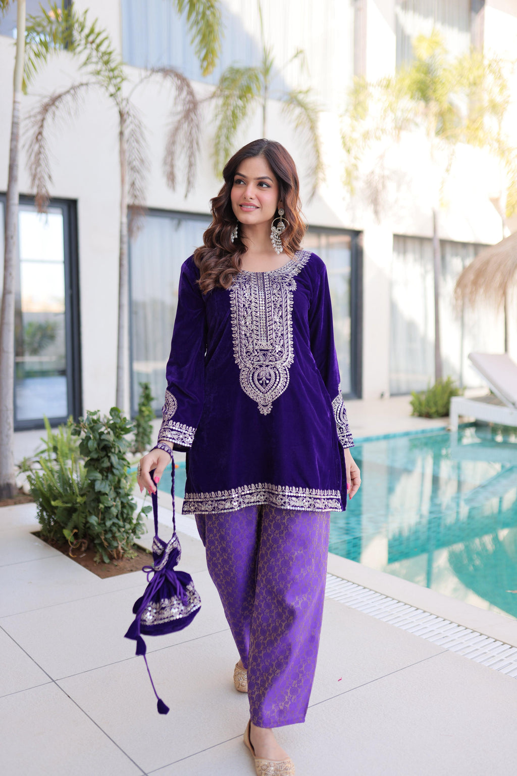 Front view of a purple velvet designer kurta with Zari coding embroidery and a matching Batwa bag.