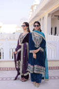 Woman wearing a luxurious Wine and Rama velvet embroidered kurta set with matching batwa bag