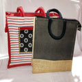 Set of two striped jute fashion bags in orange, red, black, and tan with geometric patches and zip closures.
