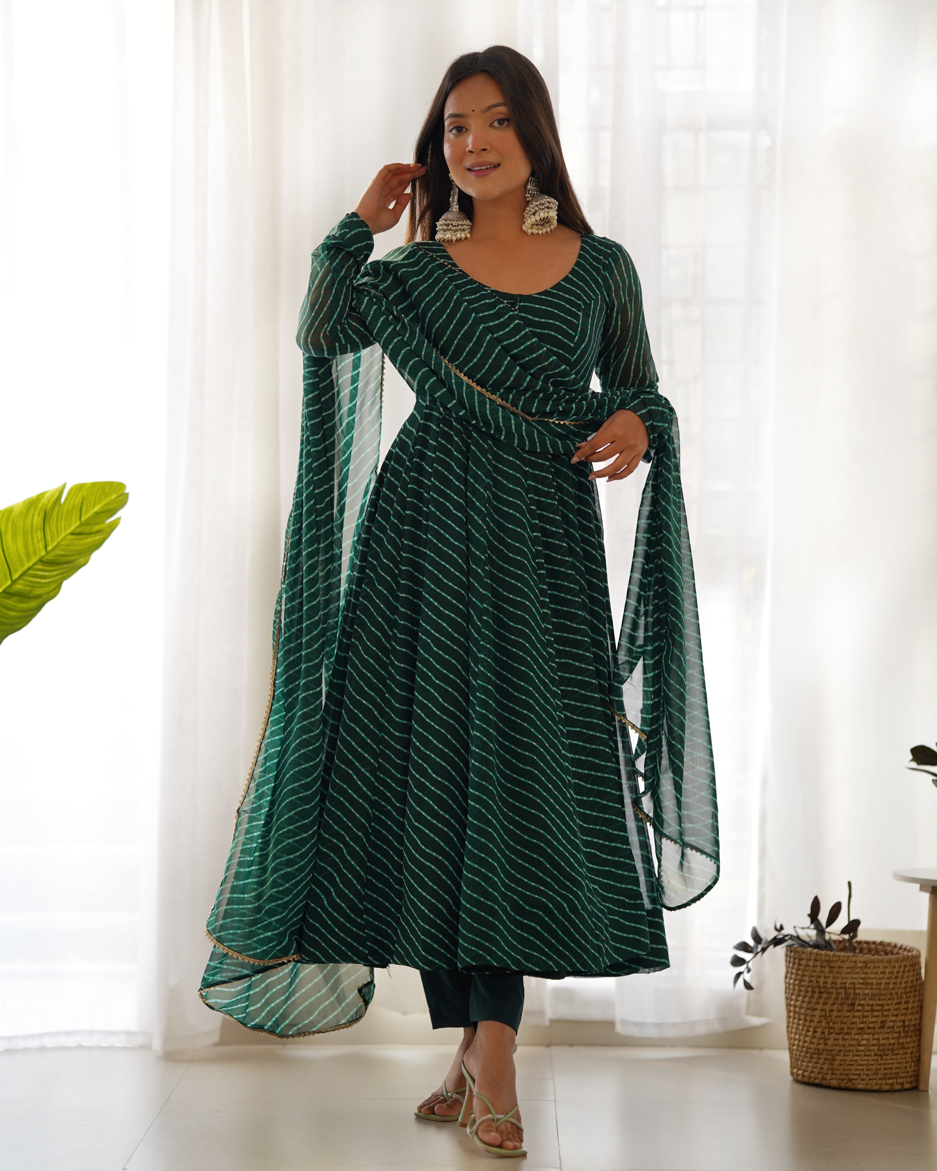 Women wearing a green laheriya print faux georgette Anarkali kurta with churidar sleeves and a matching dupatta