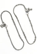 A pair of elegant oxidised silver anklets with traditional Kamal Johar designs on a neutral background.