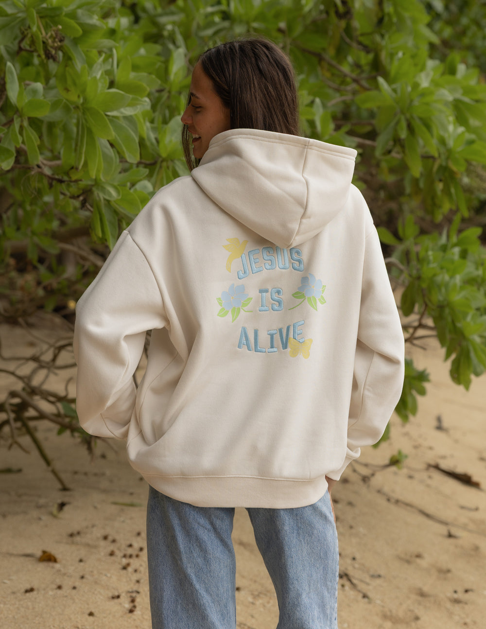 Jesus Is Alive Unisex Hoodie in Nimbus Cloud with pastel graphic text, relaxed fit, worn by model.