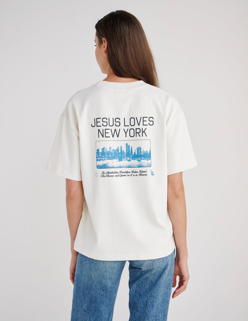 Model wearing a heavyweight Jesus Loves New York graphic t-shirt in an urban setting.