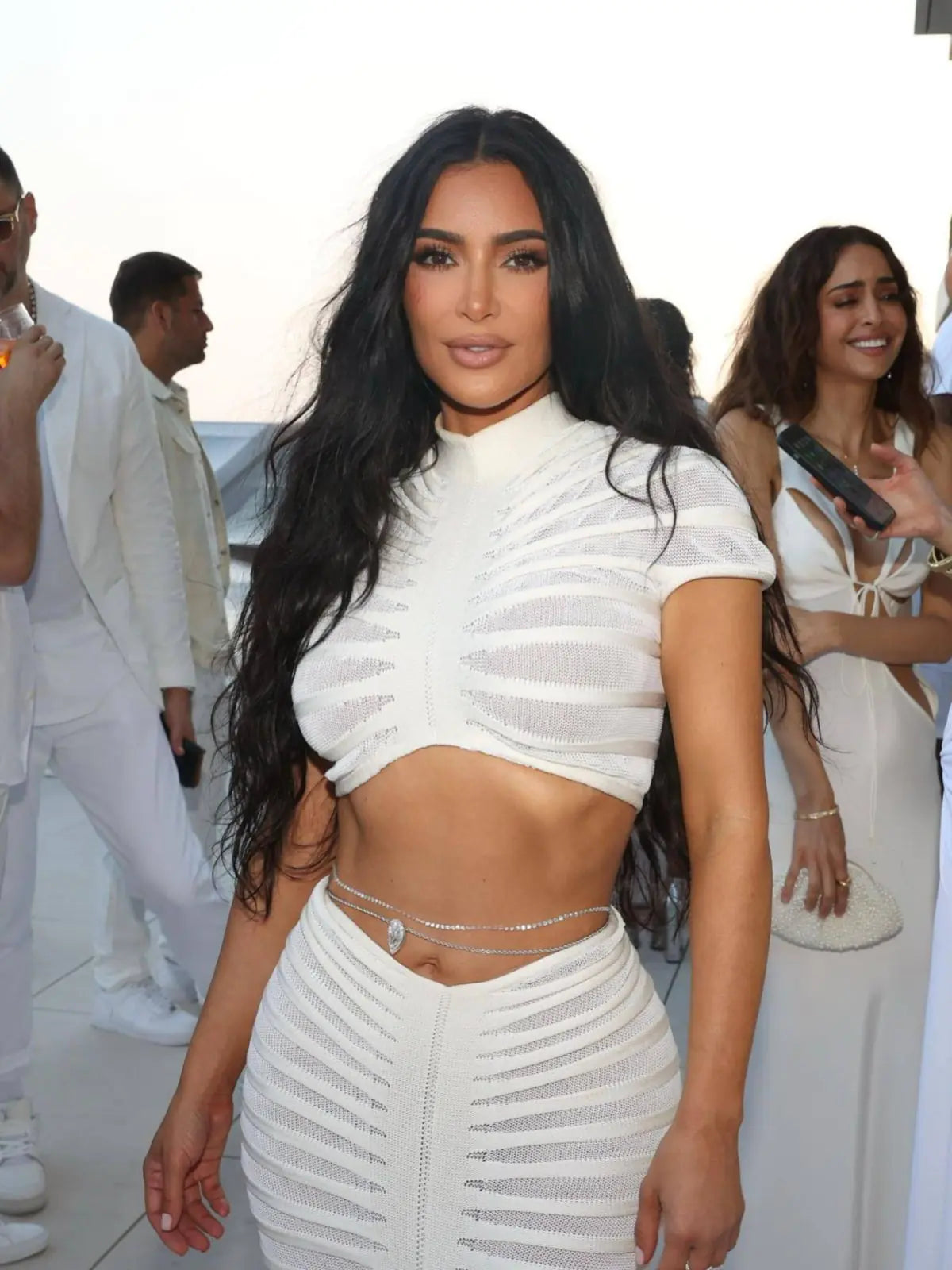 A woman wearing a two-piece white knit sheer crop top and matching skirt club outfit.