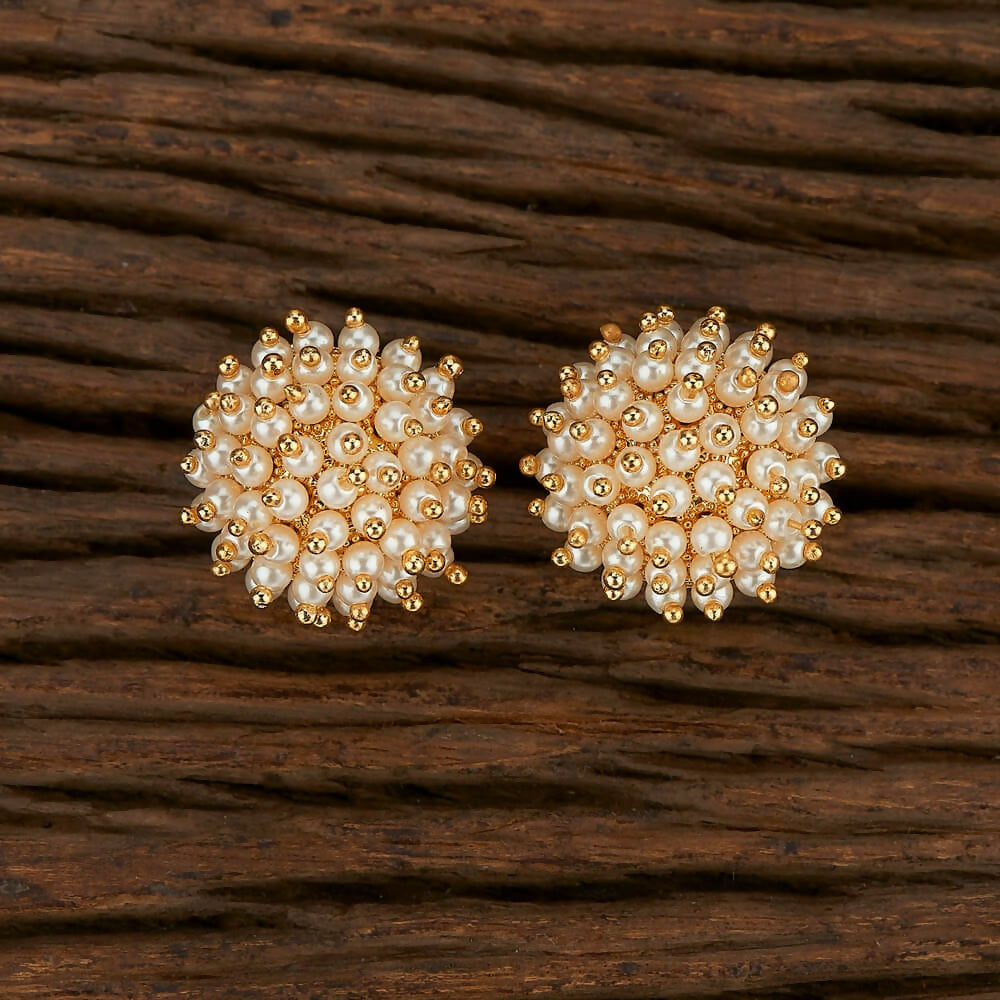 A pair of traditional golden white Kundan and pearl drop earrings displayed against a neutral background.