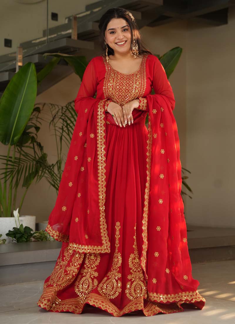 Woman wearing a vibrant red georgette gown featuring intricate gold zari embroidery and matching dupatta.