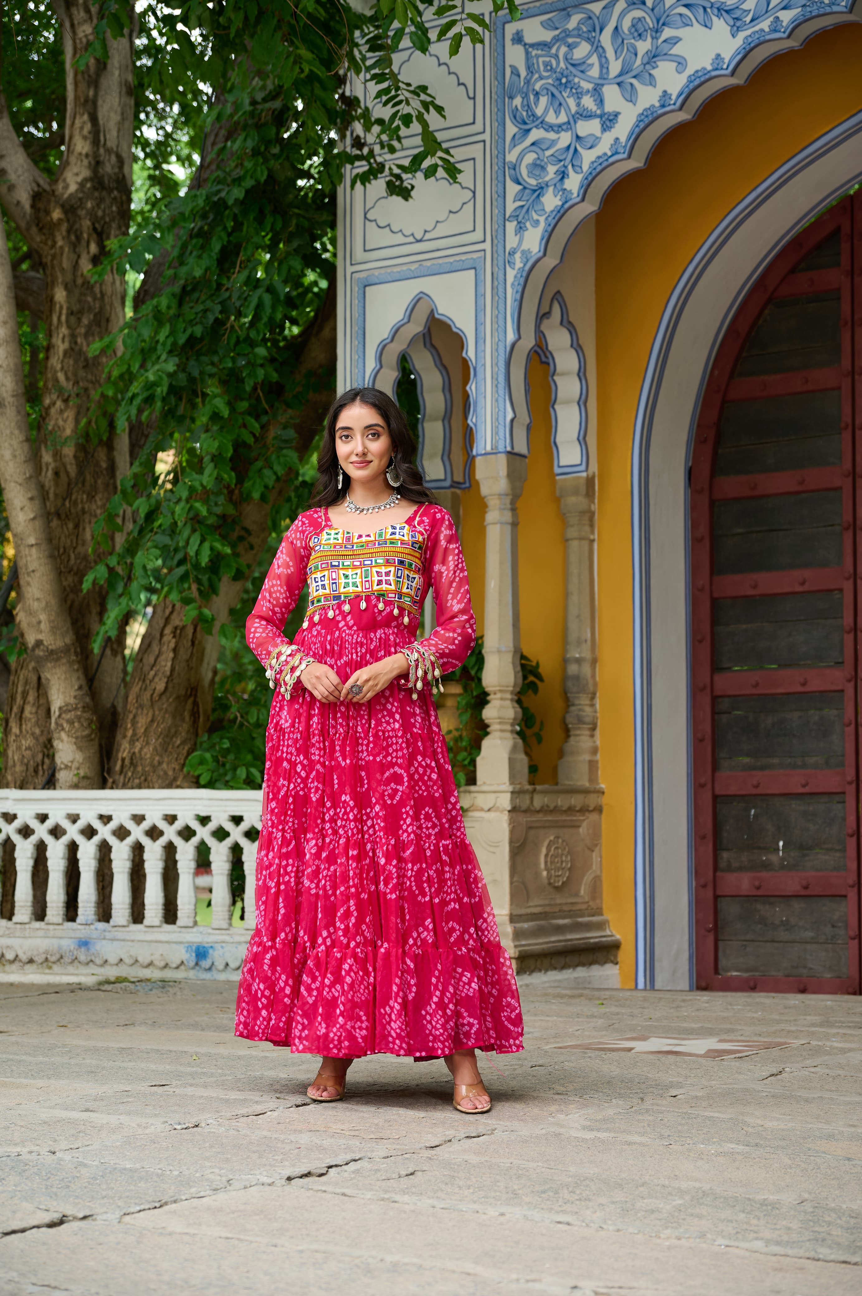 A vibrant pink georgette gown featuring traditional Bandhani print and colorful Kutchi patchwork for festive wear.