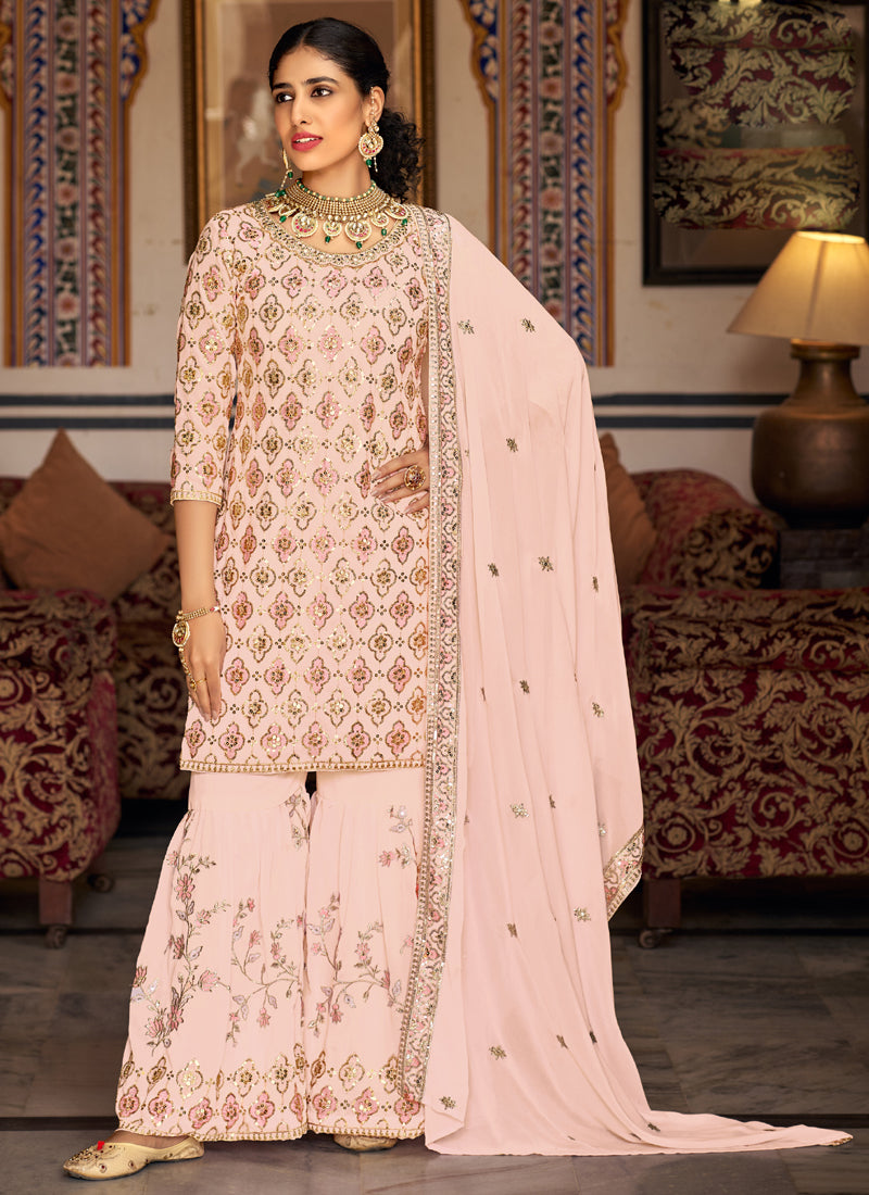 Light peach designer sharara suit in georgette fabric with intricate embroidery.