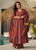 Model wearing a red muslin salwar suit with intricate digital prints and a shimmering finish